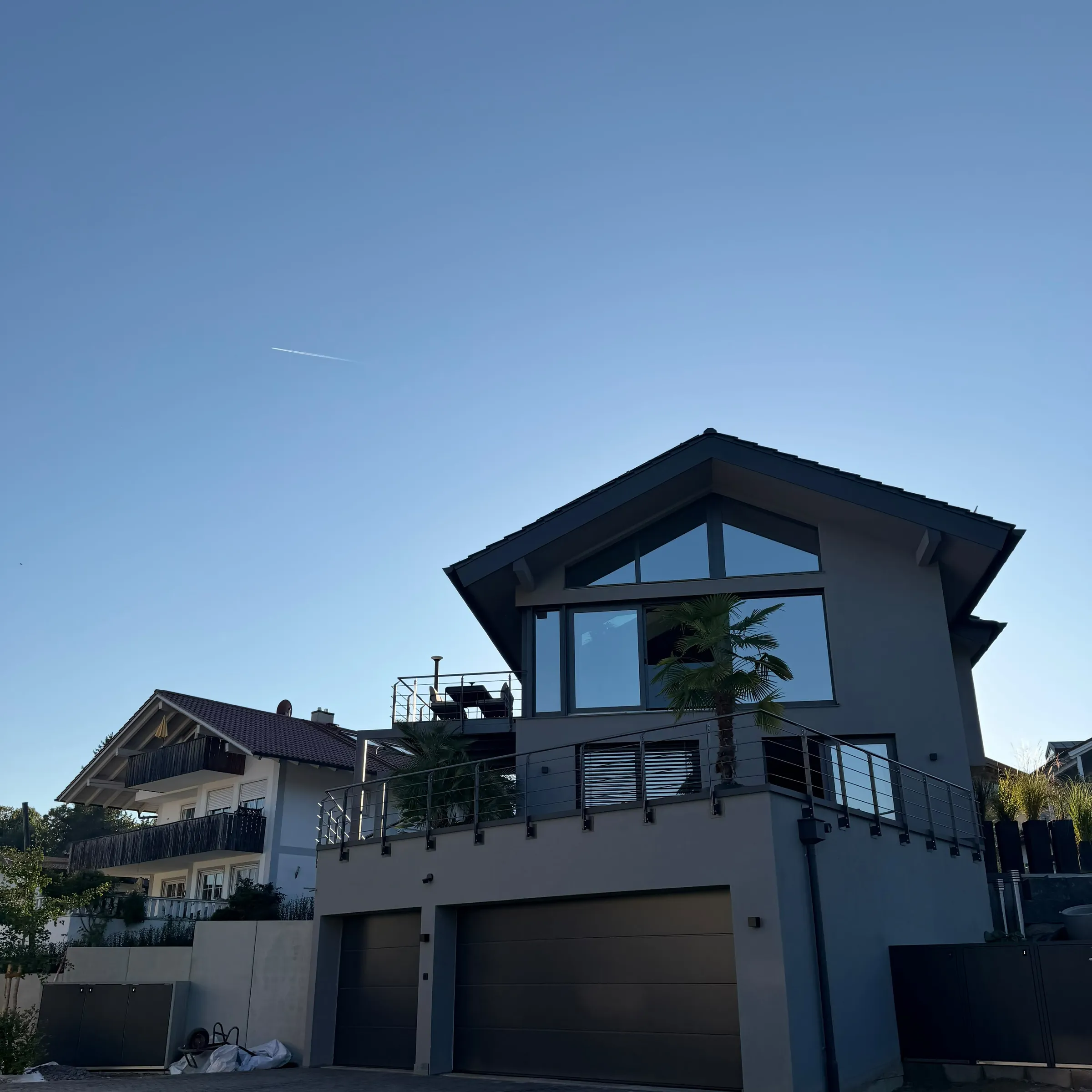 Modernes Haus mit grau verputzter Fassade, großer Giebelverglasung und Doppelgarage